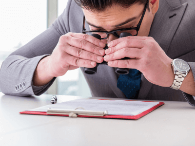 a man wearing spectacles and reading a document with the help of binaculars